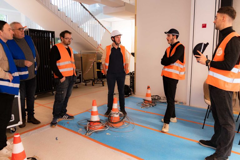 Équipe technique installant caméras et matériel audiovisuel avant une émission en direct.